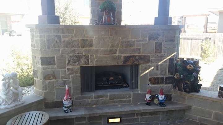 Stone outdoor fireplace with a pergola surround and curved seat walls