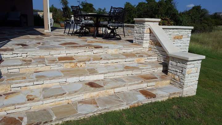 Raised flagstone patio with chopped limestone steps and a curved seat wall