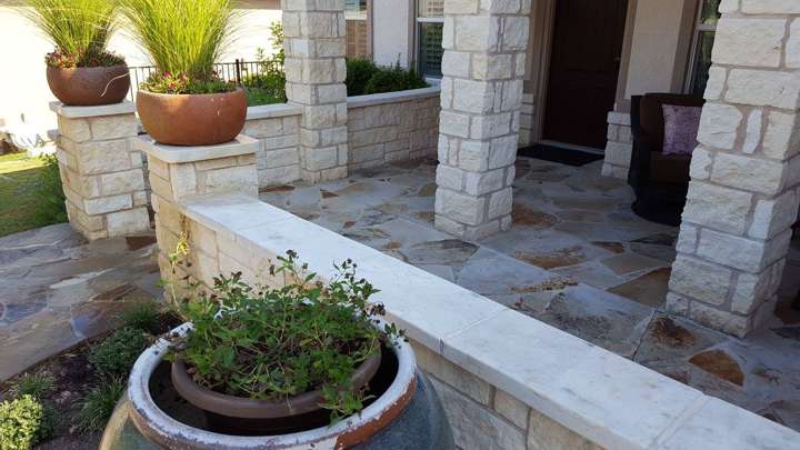 Flagstone entry with chopped limestone columns, a low seat wall and potted plants