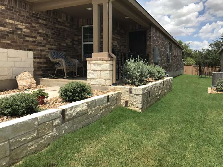 Limestone bed wall along a house with new plantings and lawn