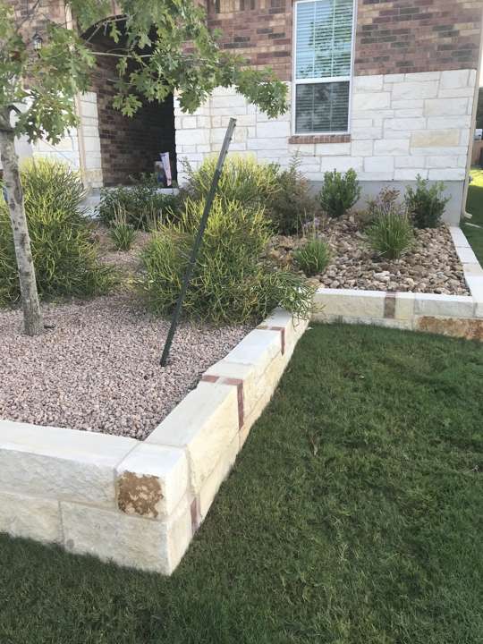 Limestone-edged bed with river rock along a side yard