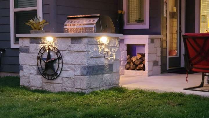 Limestone grill island with a Texas star and stacked firewood storage