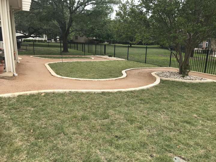 Decomposed granite path with limestone edging across a large lawn to an iron fence