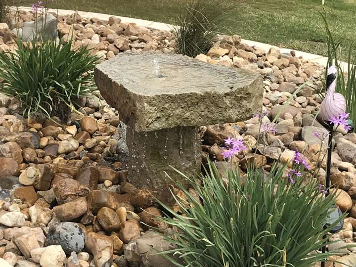 Limestone slab bubbler in a river-rock bed with native grasses