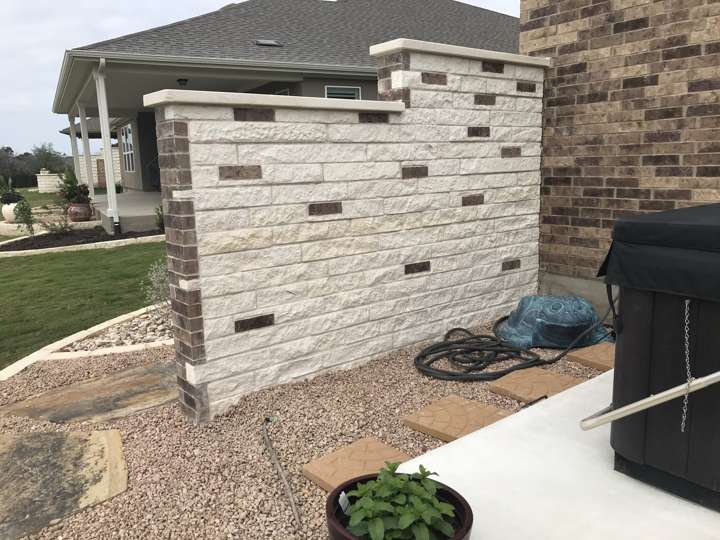 Limestone privacy wall with accent stone beside a patio
