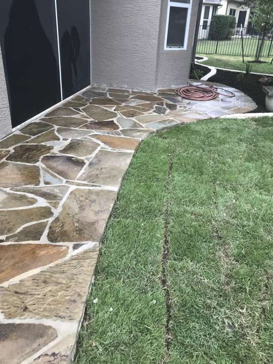 Flagstone walkway laid along a house wall beside new sod