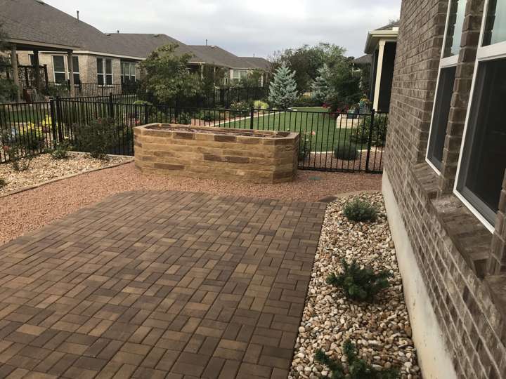 Paver patio with a limestone seat wall and iron fence beyond