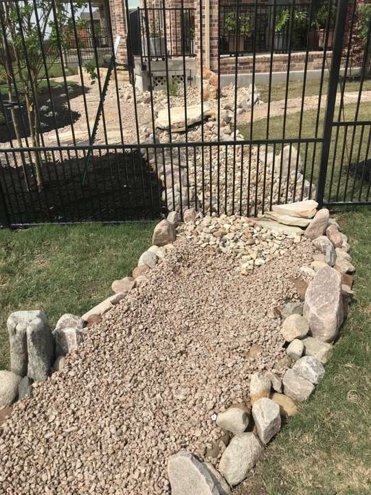 Dry creek bed and boulders inside an iron fence line