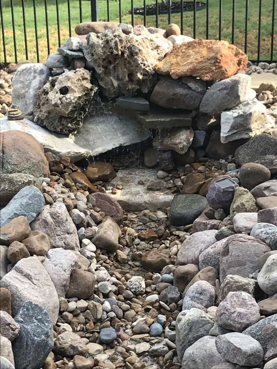 Boulder and river-rock water feature at a lawn edge
