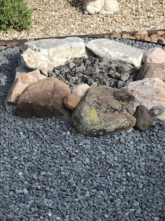 Small natural-stone fire ring set in gravel