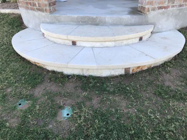 Round cut-stone landing and step set into a lawn