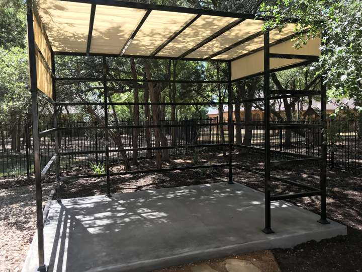 Steel pergola frame with a shade panel over a concrete pad