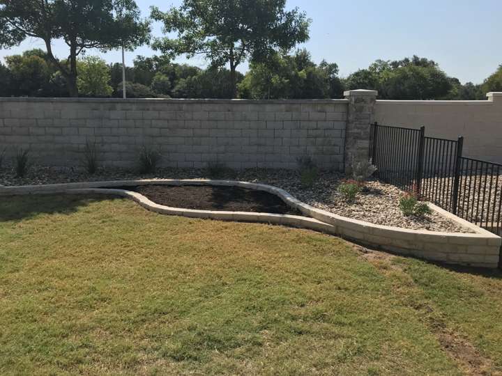 Curved limestone-edged bed with black mulch along a block wall