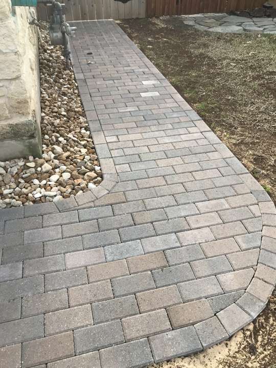 Curved paver walkway beside a mulched bed