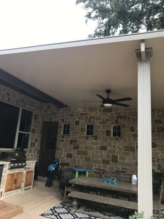 Covered patio with a ceiling fan on a stone house