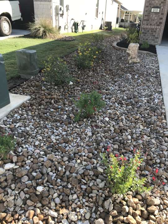 River rock and native plants along a front walk