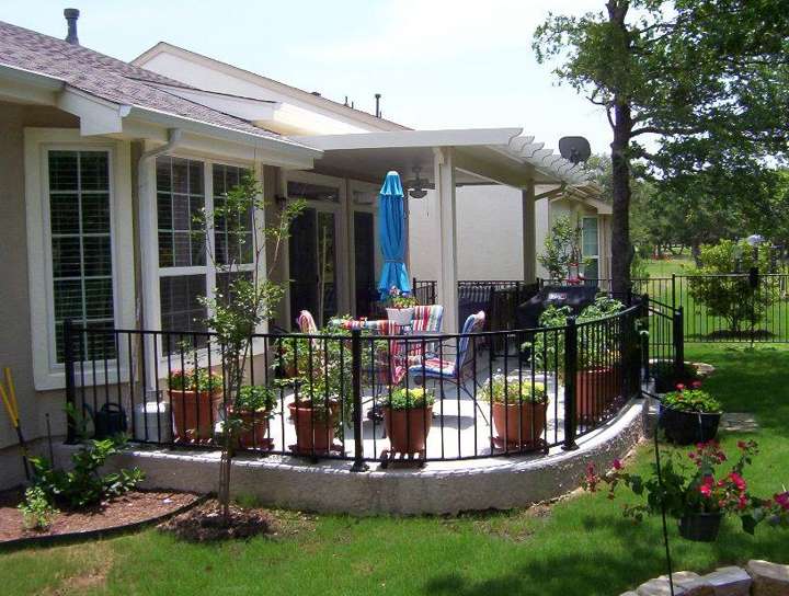 Ornamental iron fence around a raised patio with planters