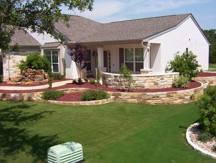 Front yard with limestone-edged beds and a raised planter at the porch