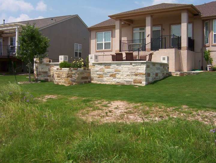 Curved limestone seat wall around a patio with mature trees behind