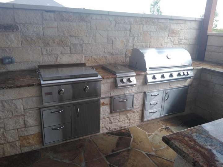 Limestone outdoor kitchen with a built-in grill and stainless doors on flagstone