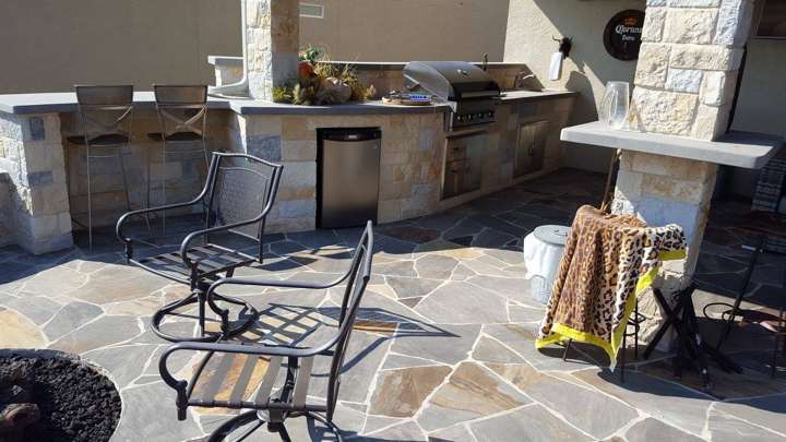 Flagstone patio with a built-in stone outdoor kitchen, bar seating and fire pit