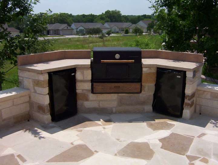 Curved limestone outdoor kitchen with grill and smoker on a flagstone patio