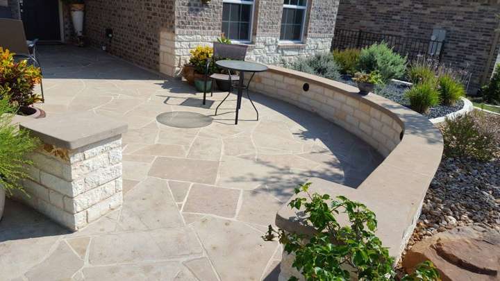Flagstone patio with a curved chopped-limestone seat wall and planted bed