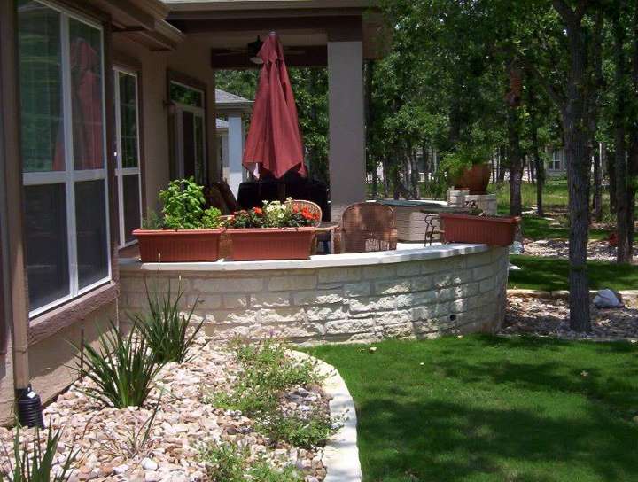 Limestone seat wall and planter bed at a back door with a red umbrella
