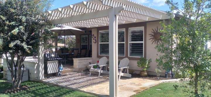 Wood pergola over a patio with seating and planted beds