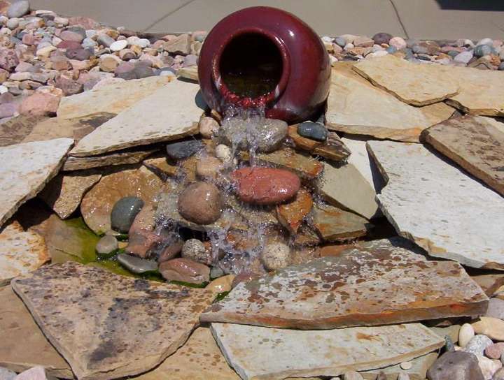Ceramic urn fountain spilling over stacked flagstone