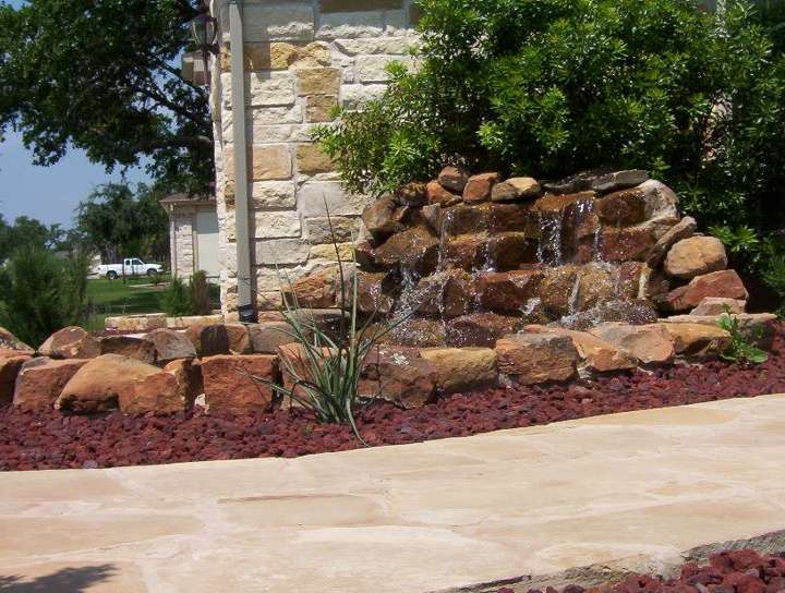 Boulder waterfall feature in a mulched bed beside a walk