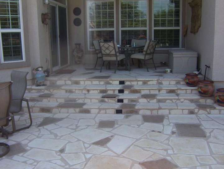 Cut-stone patio in light limestone leading to a back door with patio furniture