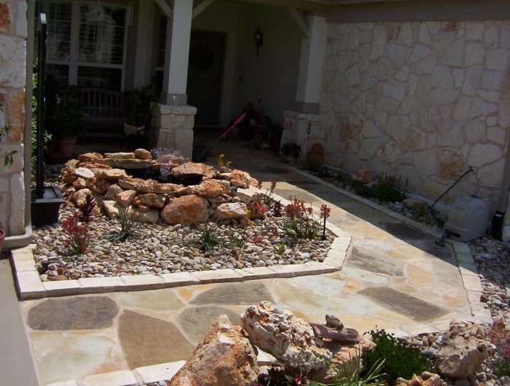 Flagstone entry walk beside a limestone bed with boulders and river rock