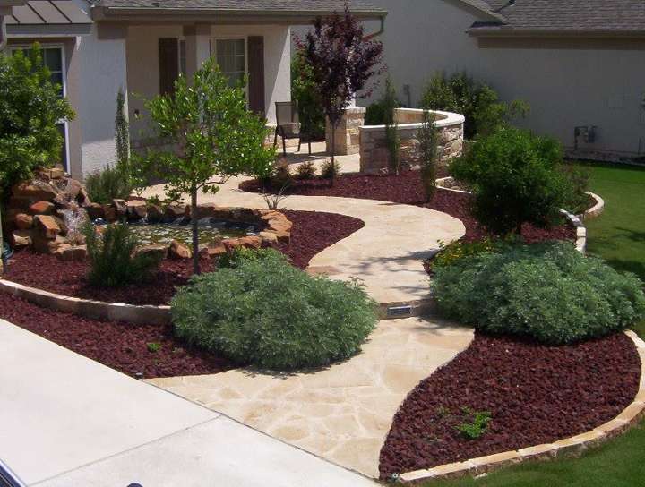 Winding flagstone front walk between mulched beds and a limestone seat wall