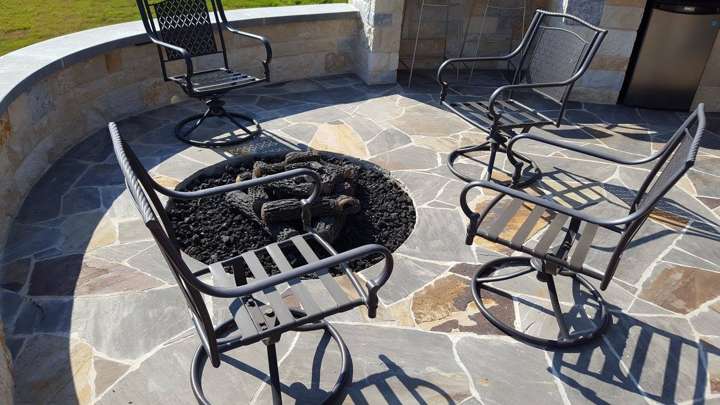 Flagstone patio with a wrought-iron dining set and a stone fire pit