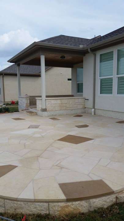 Cut-stone patio with contrasting flagstone inset beside a covered porch