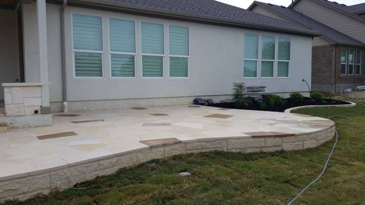 Cut-stone patio wrapping the back of a home with a low limestone edge