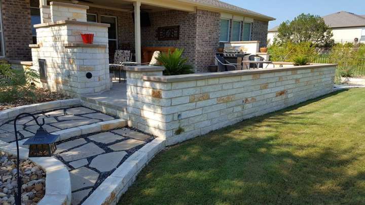Limestone seat wall and outdoor fireplace at a covered patio with a flagstone walk