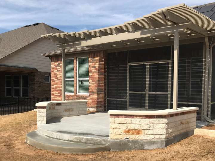 Louvered pergola over a limestone seat wall and concrete patio