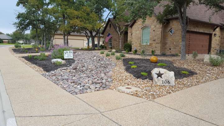 Xeriscaped front yard with a river-rock dry creek bed, limestone address boulder and native planting
