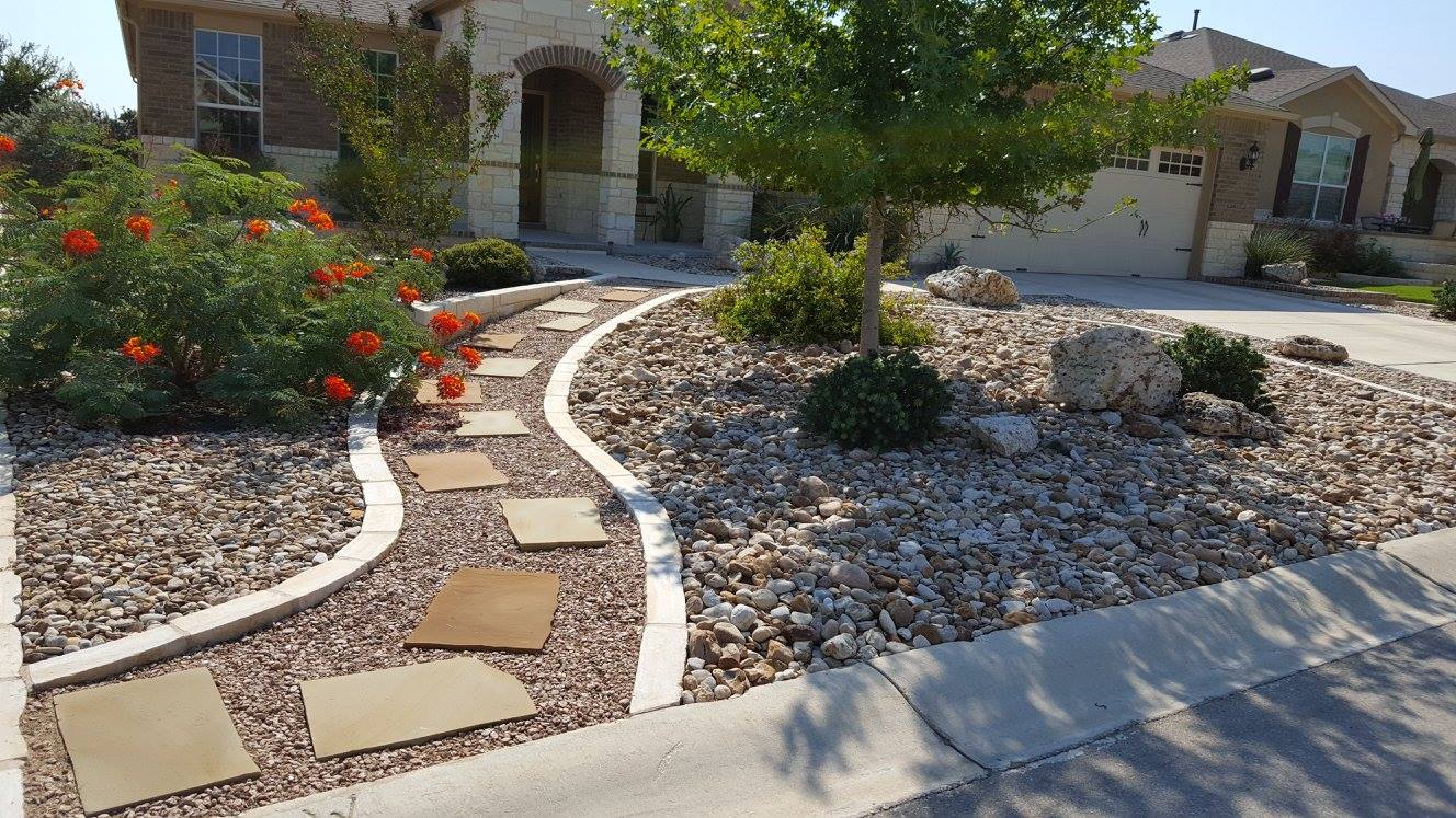 Dry creek bed of river rock winding through a xeriscaped front yard with limestone edging, a B&B project in Georgetown, Texas