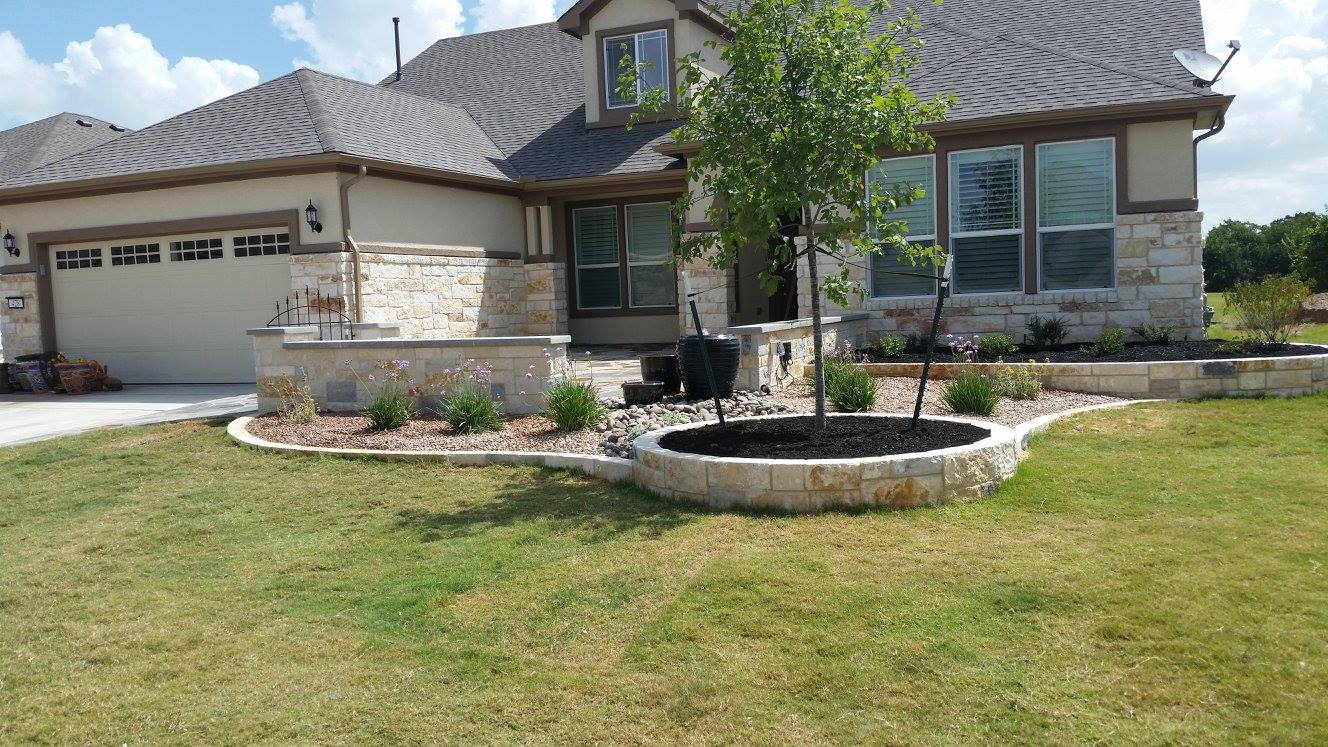 New-construction front yard with a raised chopped-limestone planter, limestone bed edging and a young shade tree, a B&B project in Georgetown, Texas