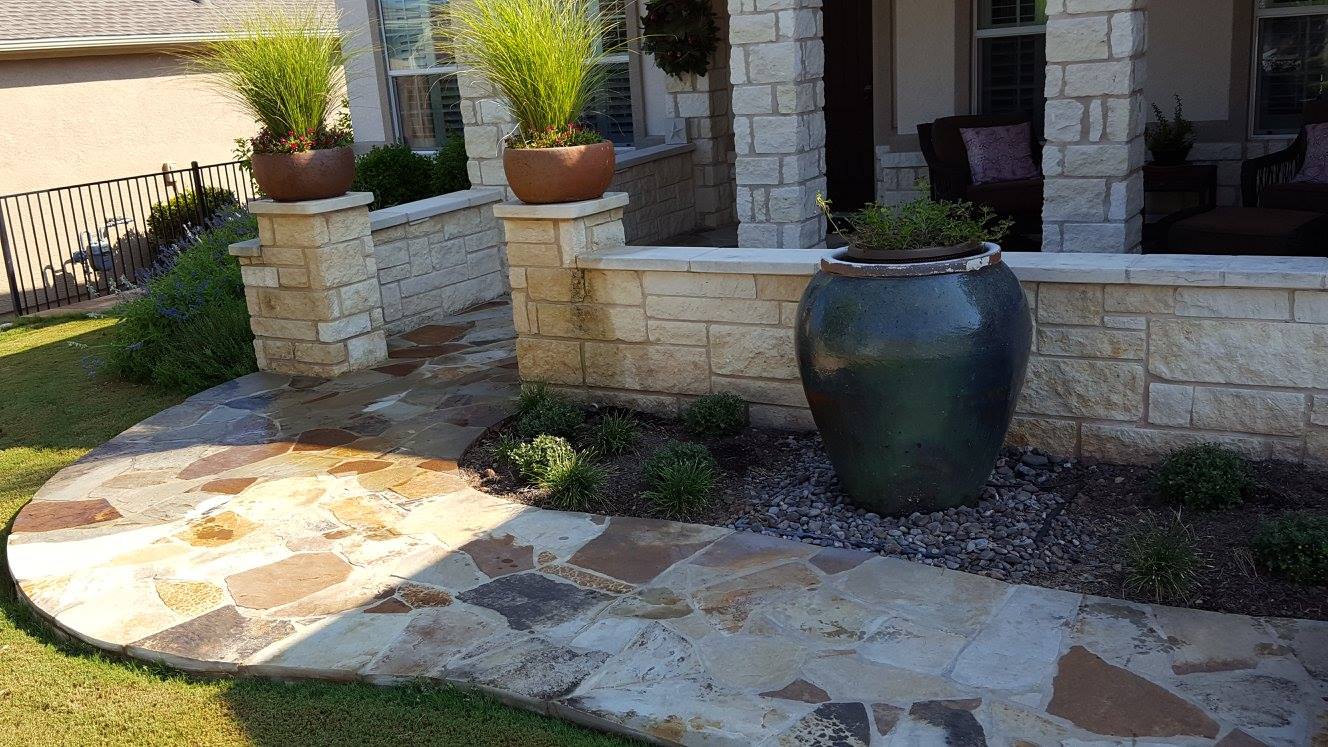 Curved flagstone walkway beside a chopped limestone seat wall and planted bed, built by B&B in Georgetown, Texas
